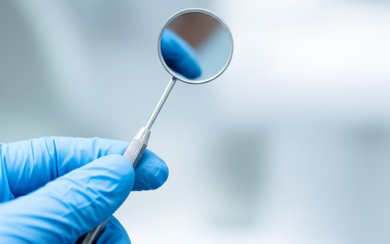 Gloved hands holding a dental tool